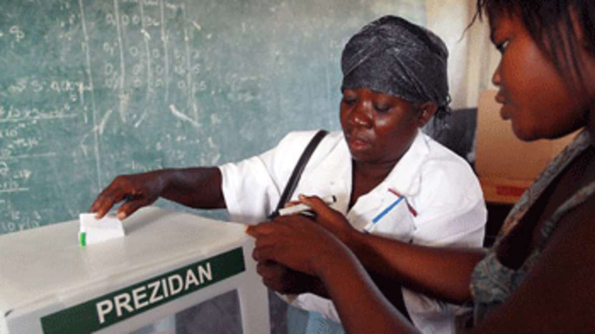 A poll worker places a mark on a voters hand to indicate she voted as she drops her ballot into the voting box during Haiti's national election (Getty Images)