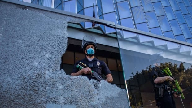 A police officer is seen through a broken glass at the U.S. Courthouse in Downtown Los Angeles, California, on July 25, 2020. (Apu Gomes/AFP)