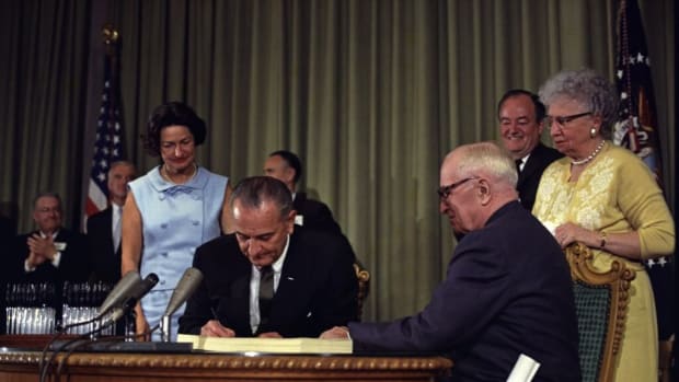 President Lyndon B. Johnson signing the Medicare Bill at the Harry S. Truman Library in Independence, Missouri, with President Truman seated next to him. Twenty years earlier, President Truman proposed his idea for nationwide health care. Archive photo from the White House Press Office