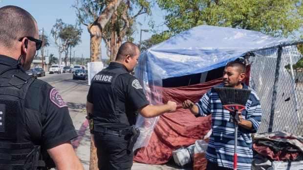 Fullerton Police officer Matt Kalscheuer, left, watches as officer Jesus Salazar fist-bumps Jose Romero at a homeless camp on Gilbert Street in Fullerton, CA on Friday, October 4, 2019. The two officers are homeless liaisons on the Delta Unit. They receive training on how to interact with people with mental issues and the homeless. (Photo by Paul Bersebach, Orange County Register/SCNG)
