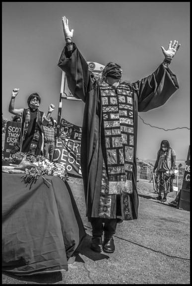 Pastor Allison Tanner leads participants in a prayer ritual outside the San Quentin gates. Rev. Deborah Lee, behind her, told the vigil that over 7,000 people in the state prison system have now tested positive for COVID-19.
