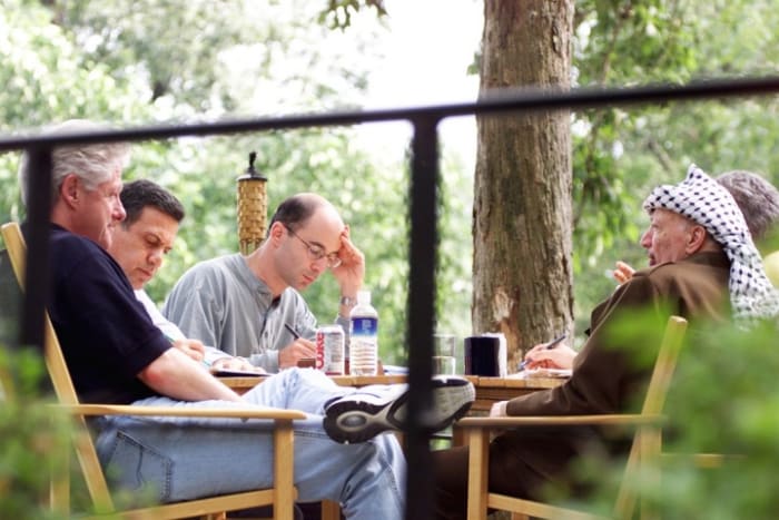 Robert Malley (center) seated with Bill Clinton and Yasser Arafat at Camp David in July. 2000. Sharon Farmer | White House