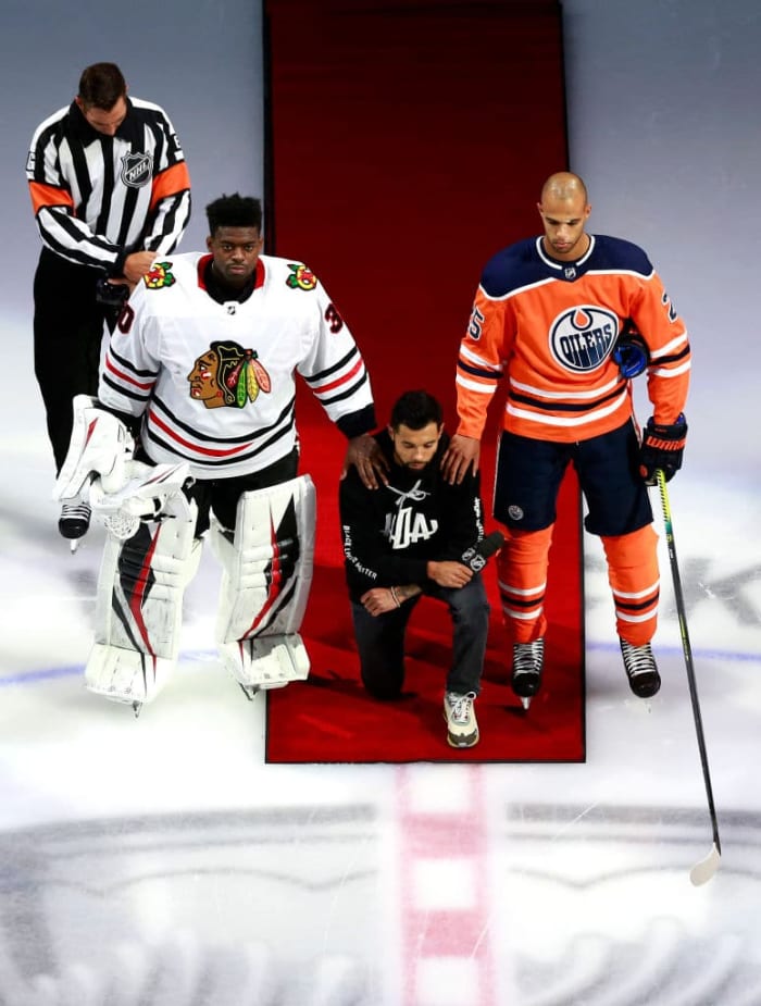 EDMONTON, ALBERTA - AUGUST 01: Malcolm Subban #30 of the Chicago Blackhawks and Darnell Nurse #25 of the Edmonton Oilers place their hands on Mathew Dumba of the Minnesota Wild during the national anthem of the United States before the Game One of the Western Conference Qualification Round prior to the 2020 NHL Stanley Cup Playoffs at Rogers Place on August 01, 2020 in Edmonton, Alberta.Dumba spoke before the game about the NHL's support of Black Lives Matter and ending racism. (Photo by Jeff Vinnick/Getty Images)
