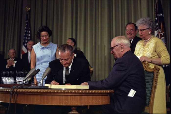 President Lyndon B. Johnson signing the Medicare Bill at the Harry S. Truman Library in Independence, Missouri, with President Truman seated next to him. Twenty years earlier, President Truman proposed his idea for nationwide health care. Archive photo from the White House Press Office