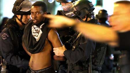LAPD officers take a young man into custody after an order to disperse was ignored at 6th and Hope streets on Wednesday night. (Brian van der Brug / Los Angeles Times)