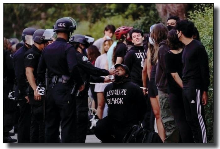 People wait to be processed by law enforcement officers on a Wilshire Boulevard sidewalk in Westwood.(Kent Nishimura / Los Angeles Times)