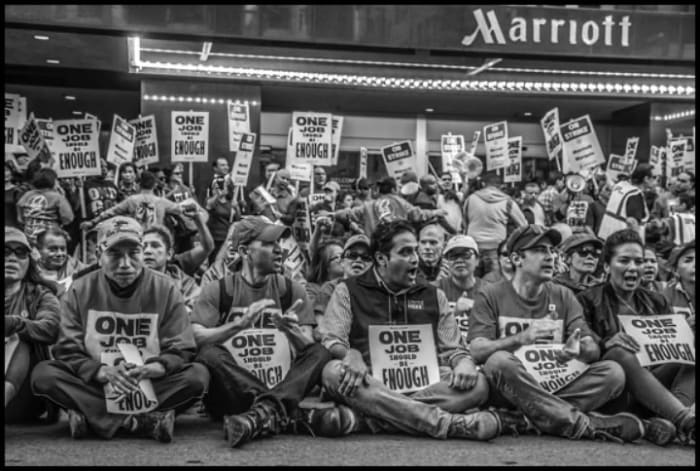 Anand Singh, Nicholas Javier and Lisa Kaid sit down in the middle of Fourth Street, in coordinated national demonstrations and civil disobedience in many cities during the Marriott strike.