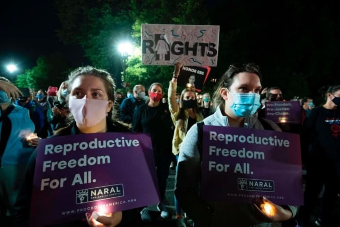 People hold signs and candles as they pay their respects to Ruth Bader Ginsburg near the U.S. Supreme Court in Washington, D.C., on September 19, 2020. (JOSE LUIS MAGANA / AFP VIA GETTY IMAGES)