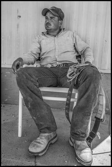 COACHELLA VALLEY, CA - 3APRIL17 - Alberto Castro works as a palmero, in the date palm groves of Coachella Valley, and has worked over 15 years in the trees. After work he sits in the shade of the trailer where he lives in a trailer park near Thermal. He holds the safety harness he is supposed to use when working, but it restricts his ability to work quickly, and he is paid by the piece rate, so he often doesn't use it.Copyright David Bacon
