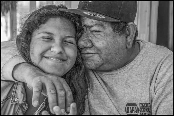 COACHELLA VALLEY, CA - 3APRIL17 - Carlos Chavez works as a palmero, in the date palm groves of Coachella Valley, and has worked over 20 years in the trees. After work he sits in the shade of the trailer where he live with his daughter Michelle, in a trailer park near Thermal. Michelle is in high school, trying to win a scholarship so she can go to college. Carlos took her to work with him one summer, but she didn't like it, and says it motivated her to study harder.Copyright David Bacon