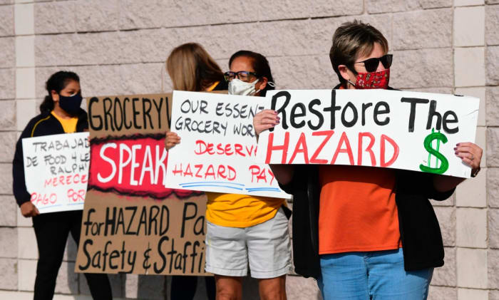 Supermarket workers hold placards in protest in front of a Food 4 Less supermarket in Long Beach, California on February 3, 2021, after a decision by owner Kroger to close two supermarkets rather than pay workers an additional $4.00 in "hazard pay" for their continued work during the coronavirus pandemic. - Kroger, which owns Ralphs and food 4 Less, said it will close one of each store in April after the Long Beach city council passed a law mandating "hazard pay" for grocery store workers. Long Beach was the first city in the region to approve a hazard pay ordinance. (Photo by Frederic J. BROWN / AFP) (Photo by FREDERIC J. BROWN/AFP via Getty Images)