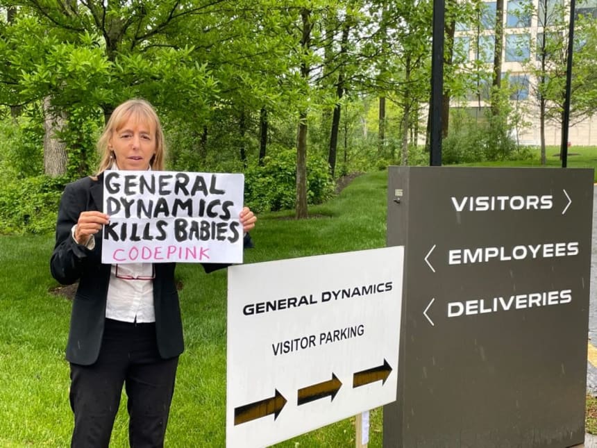 CODEPINK co-founder Medea Benjamin standing outside of General Dynamics’ headquarters in Reston, Virginia holding a sign that reads “General Dynamics kills babies”. Benjamin interrupted last year’s General Dynamics shareholder meeting on May 5, 2021. (Photo: Medea Benjamin)
