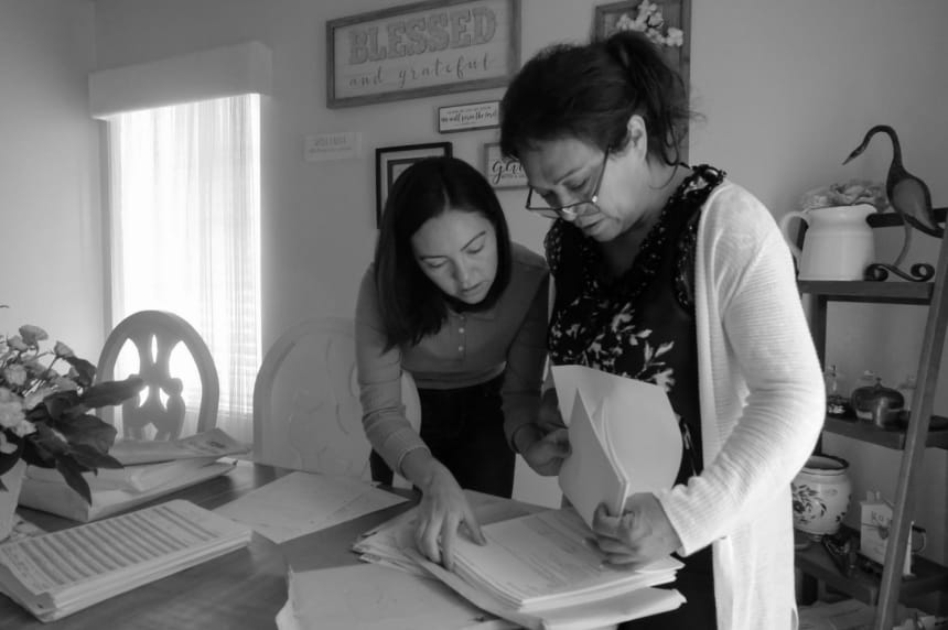 Inside their home, Debbie helps Leonor look through Hugo’s medical records. July 12, 2022. Photo by Zaydee Sanchez for palabra.
