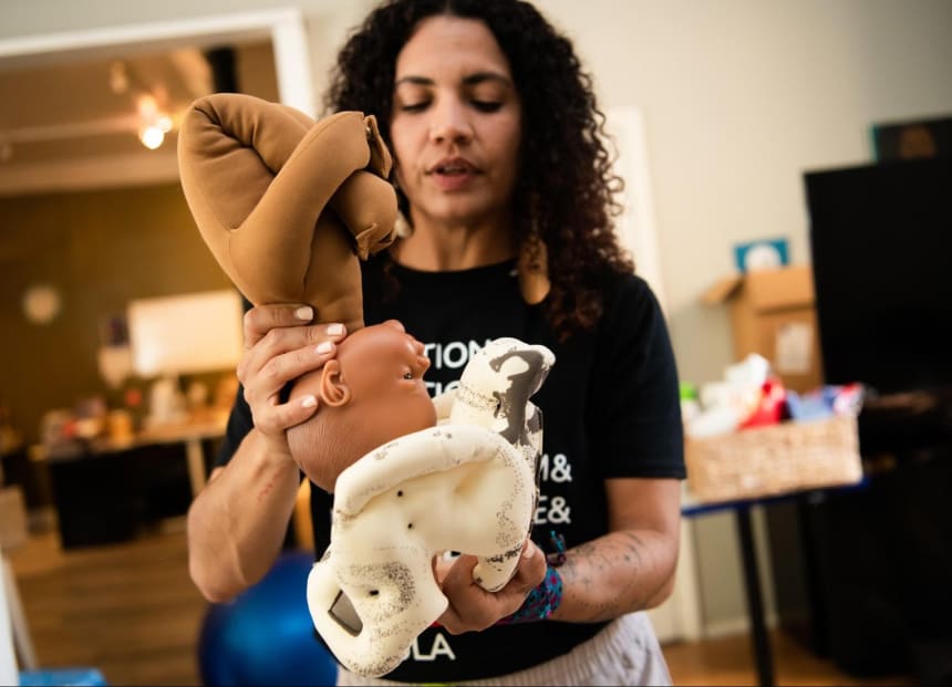 Anabel Rivera uses a baby doll to teach Zoom clases; here, she visually describes positions a baby takes in relation to the pelvis during labor. Photo by Mariela Murdocco for palabra