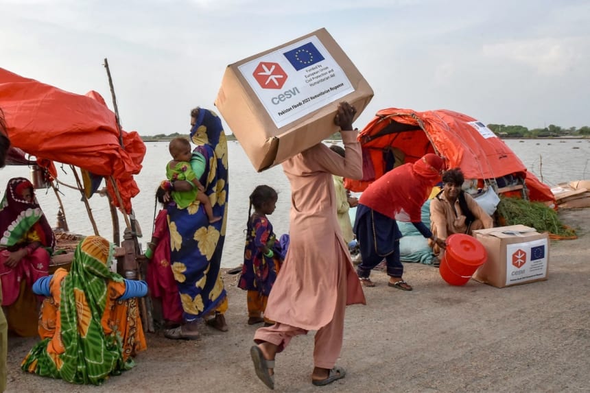 A man carries relief items along the only surviving road in a flooded region in Pakistan in Sept., 2022. Image by Abdul Majeed/European Union via Flickr (CC BY 2.0).