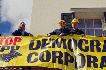 Margaret Flowers, MD and Steve Bray chained together by bike locks on the balcony of USTR with staff member standing nearby. Photo by Anne Meador