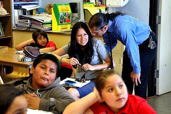 Marcos Aguilar, executive director and co-founder of Academia Semillas del Pueblo, talks with his wife, Minnie Ferguson, also a founder, during a fifth-grade class.