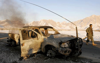 An Afghan policeman walks past a vehicle that had carried U.S. civilian contractors, after it was targeted by a suicide bomber in the Logar province. (Farzana Wahidy/AFP/Getty Images/January 2007 file photo)