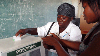 A poll worker places a mark on a voters hand to indicate she voted as she drops her ballot into the voting box during Haiti's national election (Getty Images)