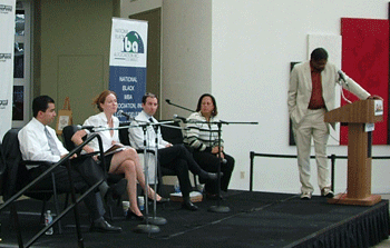 Mary Jane Stevenson addressing the audience, with Rep. Laura Richardson and Anthony Samad at right.