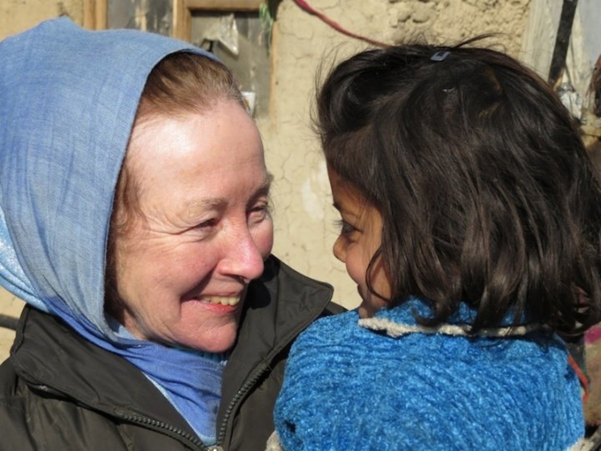 Kathy Kelly holds Shoba at the Chamin-E-Babrak refugee camp in Kabul, Afghanistan, in January 2014, a few days after the child had been saved from a burning tent, during a fire that destroyed much of the camp. (Abdulhai Darya)