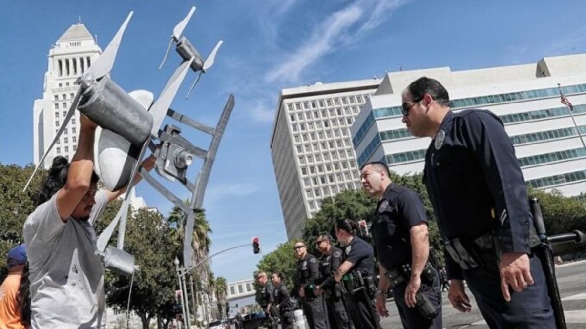 Activist Miguel Guzman holds a drone replica in front of Los Angeles police officers after a small group of protesters blocked downtown traffic last fall to oppose the Police Commission's vote to allow the department to test the devices. (Robert Gauthier / Los Angeles Times)
