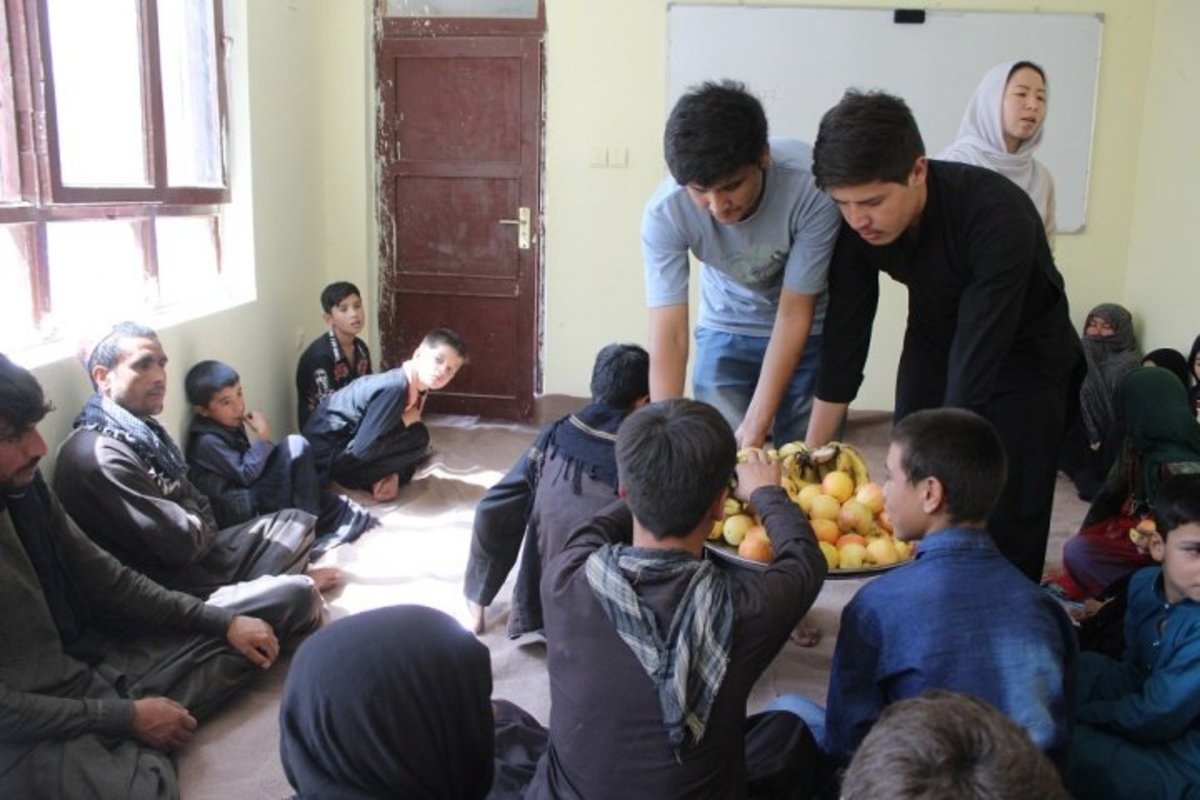 Habib (standing, left) serves fruit to parents at the Borderfree Street Kids School (Photo credit: Dr. Hakim)