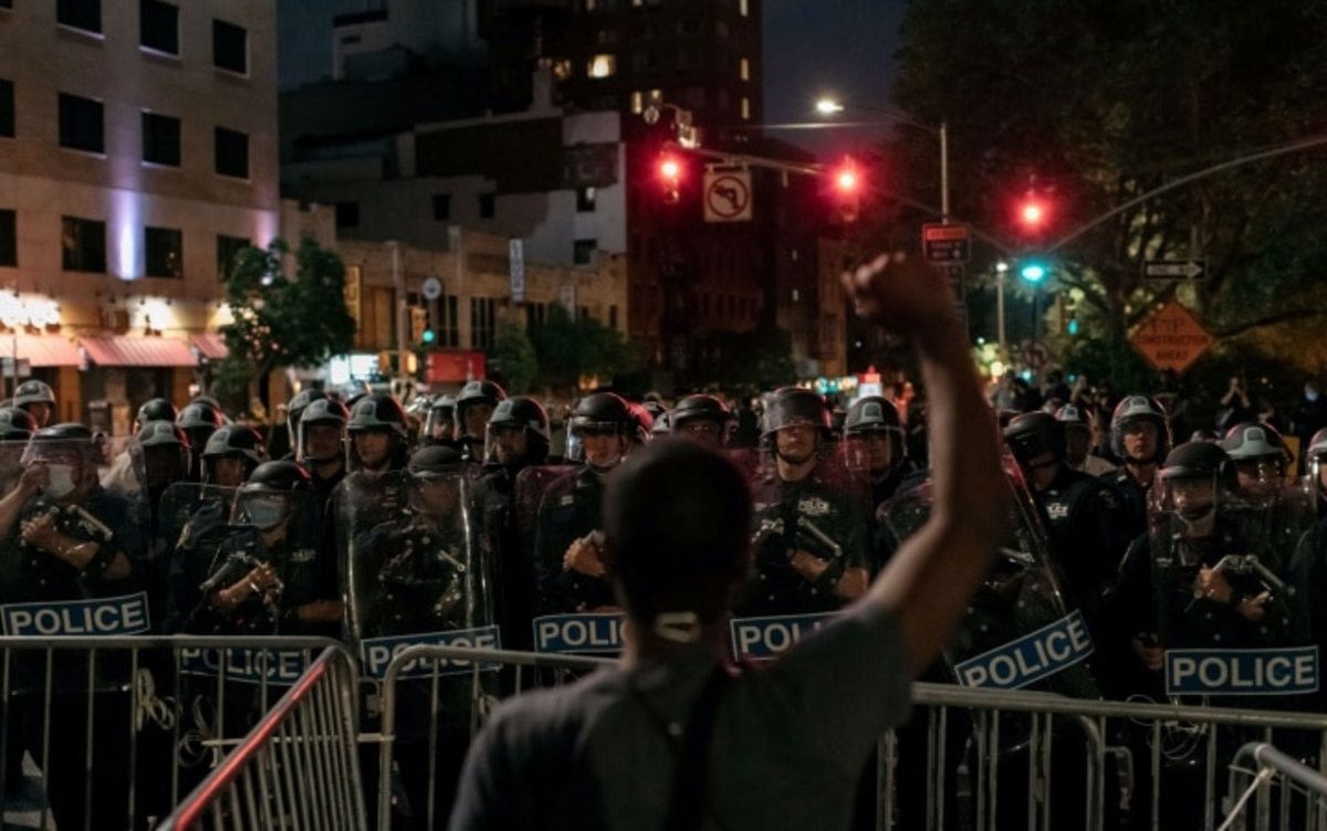 A man protesting police brutality and systemic racism holds up his hands as he faces police during a citywide curfew in New York City on June 2, 2020. Scott Heins / Getty Images