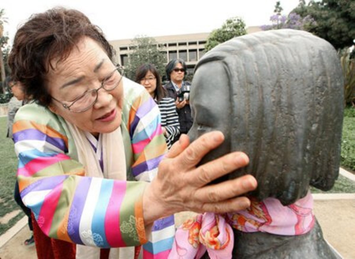 Former comfort woman Yong Soo Lee touches the face of the Comfort Women memorial in Glendale, California's Central Park.