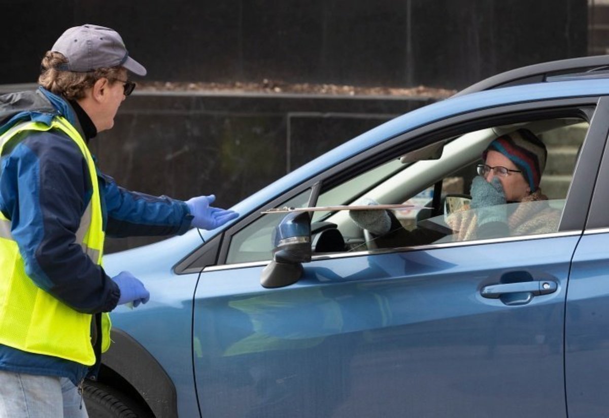 Madison poll worker Jon Becker assists a person taking advantage of drive-through voting Friday. (Mark Hoffman/AP)