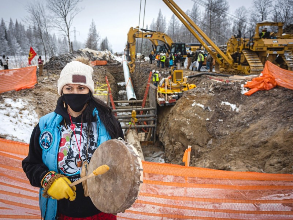 Gio Cerise, a member of the White Earth Nation, plays a drum and prays in front of Line 3 pipeline construction on Highway 169 south of Hill City, Minn. (Photo: Ben Hovland)