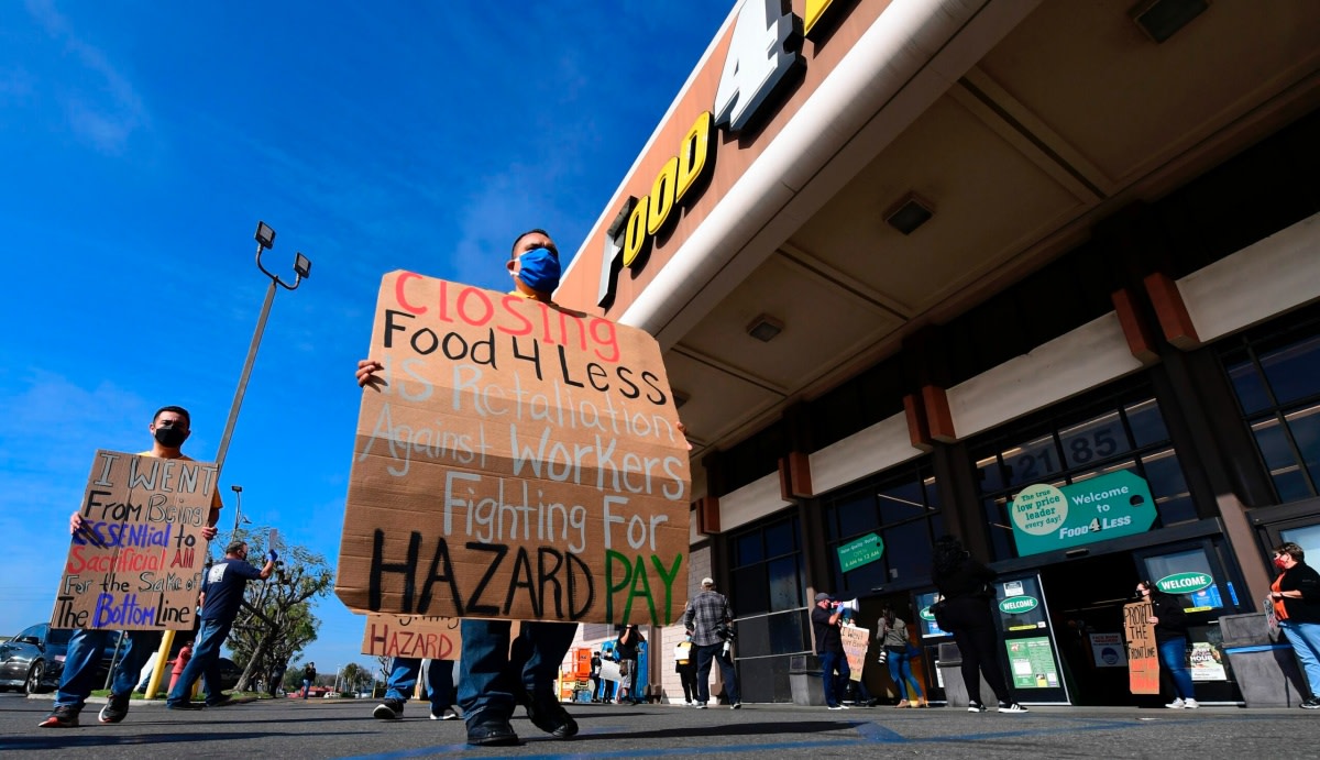 Supermarket workers hold placards in protest in front of a Food 4 Less supermarket in Long Beach, California on February 3, 2021, after a decision by owner Kroger to close two supermarkets rather than pay workers an additional $4.00 in "hazard pay" for their continued work during the coronavirus pandemic. - Kroger, which owns Ralphs and food 4 Less, said it will close one of each store in April after the Long Beach city council passed a law mandating "hazard pay" for grocery store workers. Long Beach was the first city in the region to approve a hazard pay ordinance. (Photo by Frederic J. BROWN / AFP) (Photo by FREDERIC J. BROWN/AFP via Getty Images)