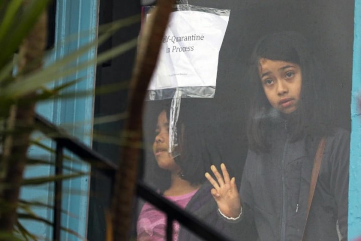 Sisters Meztli Escudero, 8, left, and Victoria Escudero, 10, stand in the window of a vacant house they and their families occupied on Saturday morning. (Irfan Khan / Los Angeles Times)