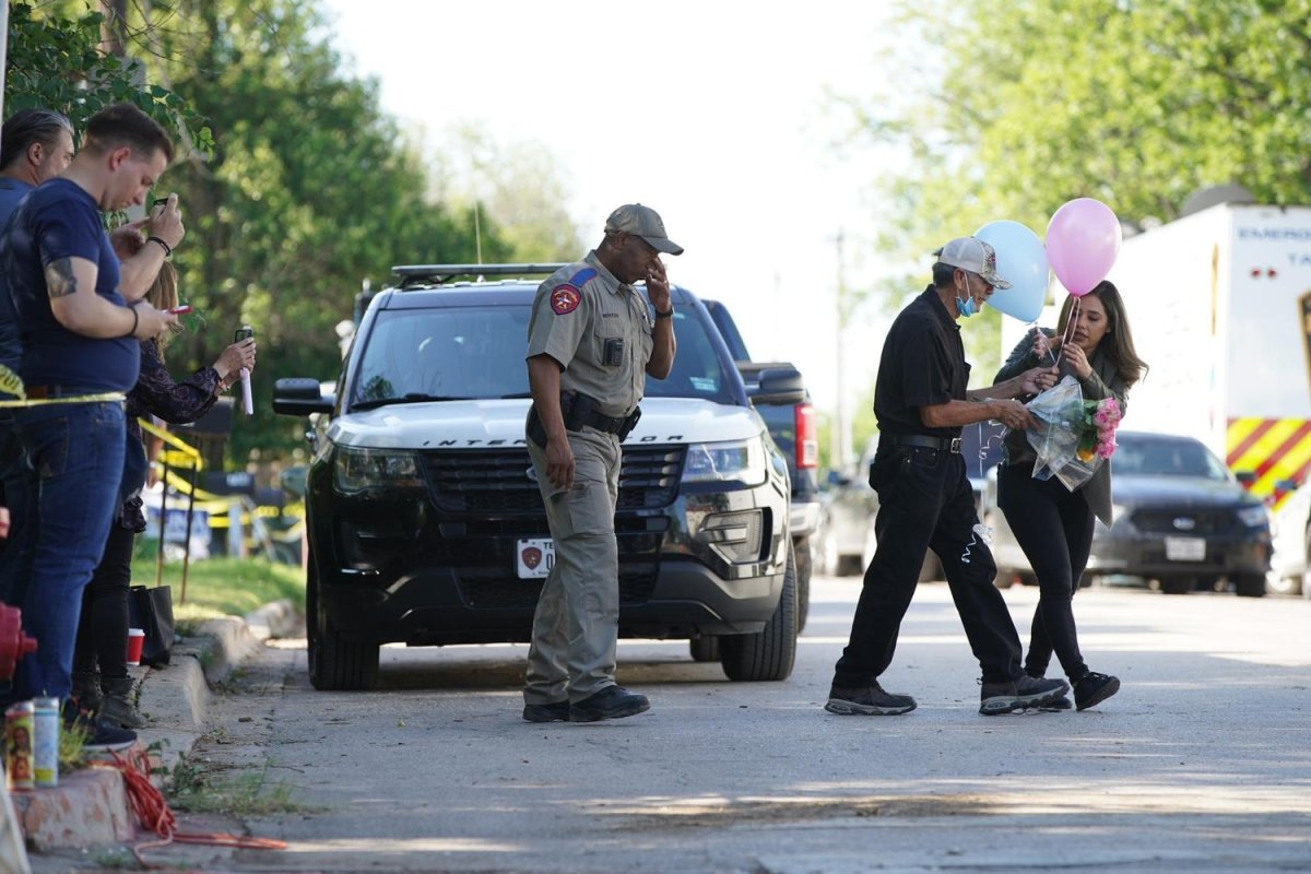 George Rodríguez, grandfather of 10-year-old shooting victim José Flores Jr., crosses the street to bring flowers and balloons to a memorial outside Robb Elementary School, with help from reporter Lidia Terrazas of Univision San Antonio. Photo by Jinitzail Hernández via Shutterstock
