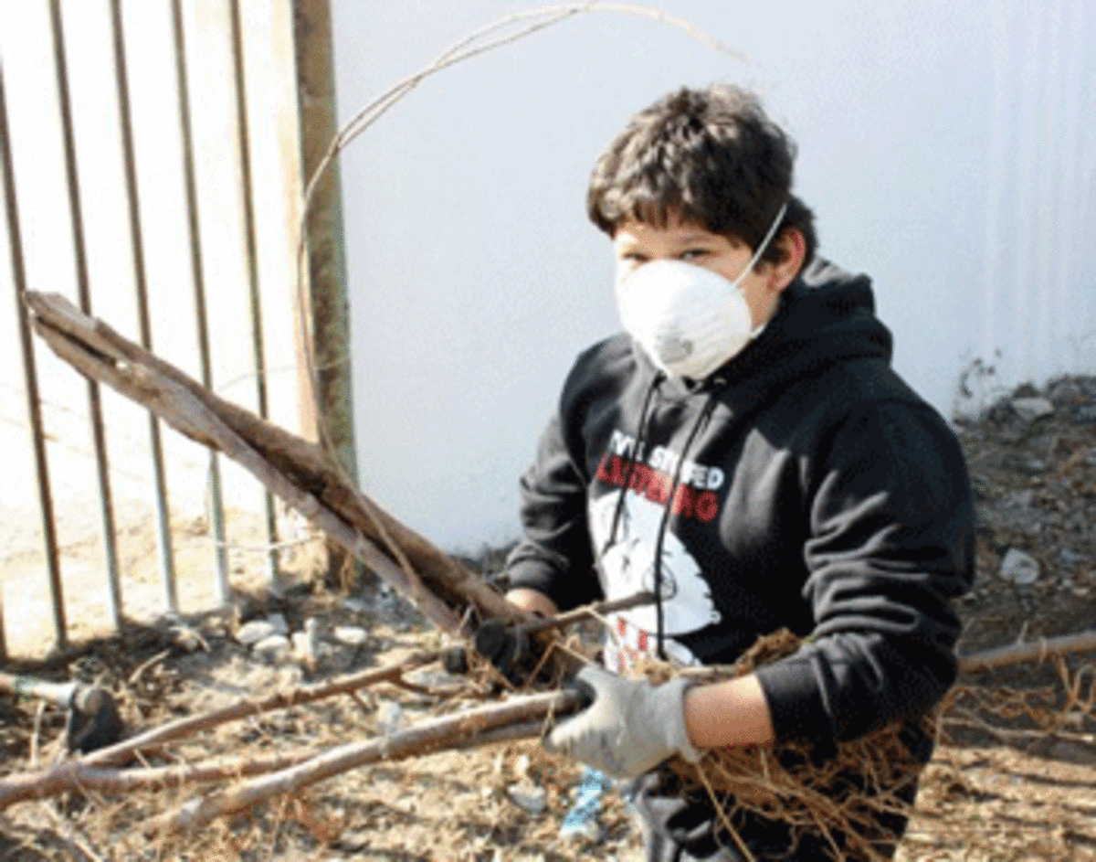 Adan Muñoz, 11, lends a hand. His family recently moved into the neighborhood. He would like to see the alley behind their home become a garden.