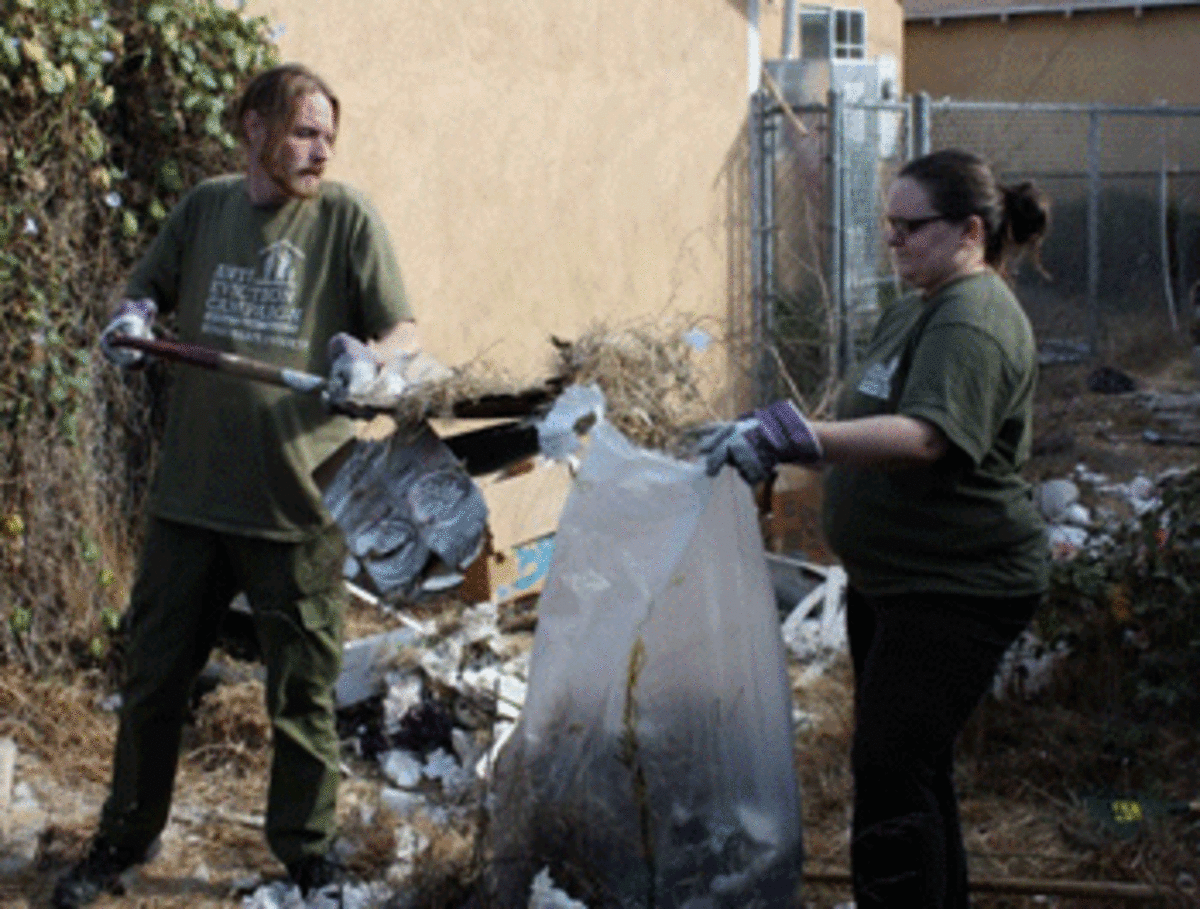 Adam Rice, co-chair of the Los Angeles Anti-Eviction Campaign, and organizer Callie Little, pick up trash in a South LA alley. Their goal, along with residents, is to clean the alley and hopefully turn it into a garden or place where children can play.
